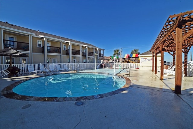 pool with a patio, fence, and a pergola