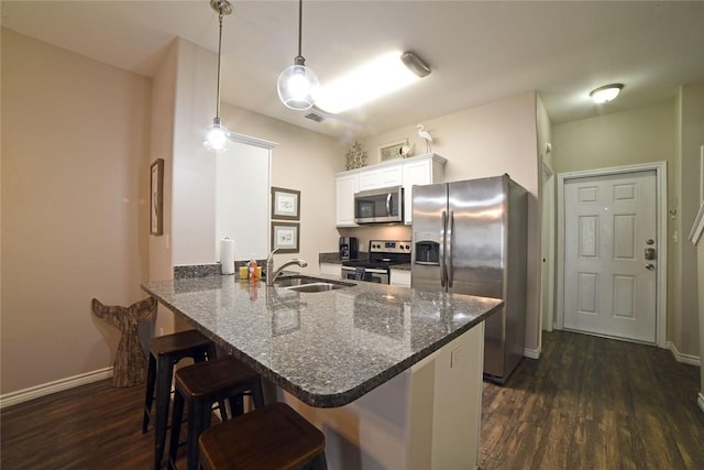kitchen with a breakfast bar area, dark wood-style floors, a peninsula, a sink, and stainless steel appliances