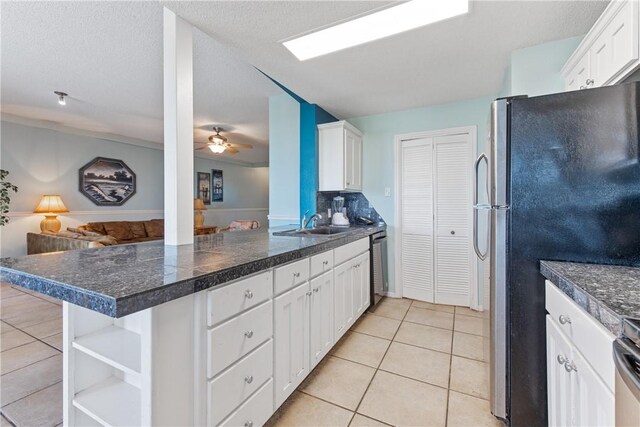 kitchen featuring open floor plan, a peninsula, light tile patterned flooring, white cabinets, and stainless steel appliances