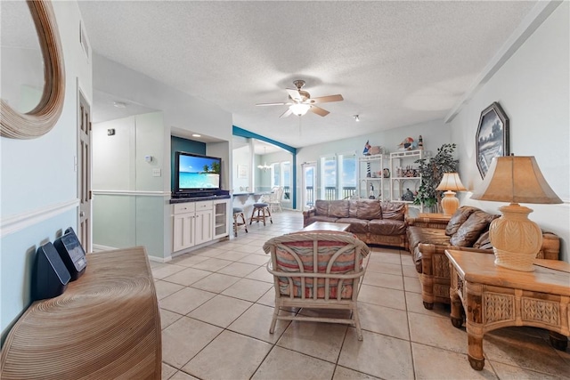 living area with light tile patterned floors, visible vents, a textured ceiling, and ceiling fan