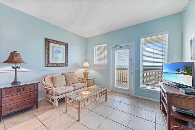 living area featuring light tile patterned floors, baseboards, and a textured ceiling