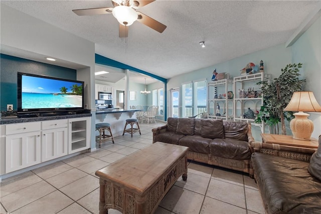 living room with light tile patterned floors, a ceiling fan, and a textured ceiling