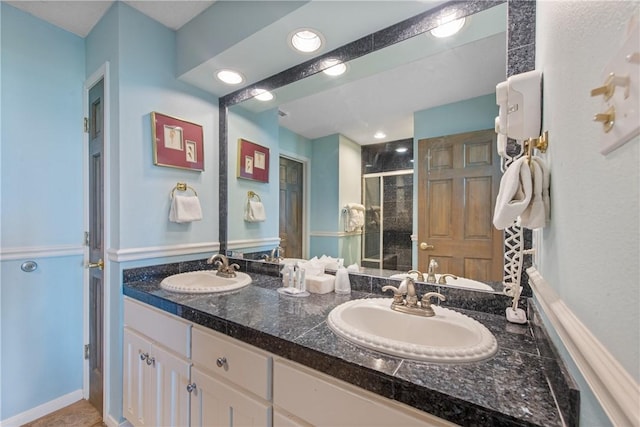 full bath featuring double vanity, recessed lighting, a shower stall, and a sink