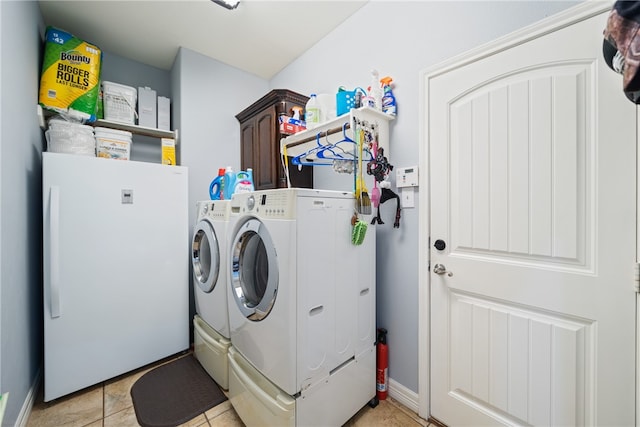 laundry room with washing machine and clothes dryer, cabinets, and light tile patterned floors