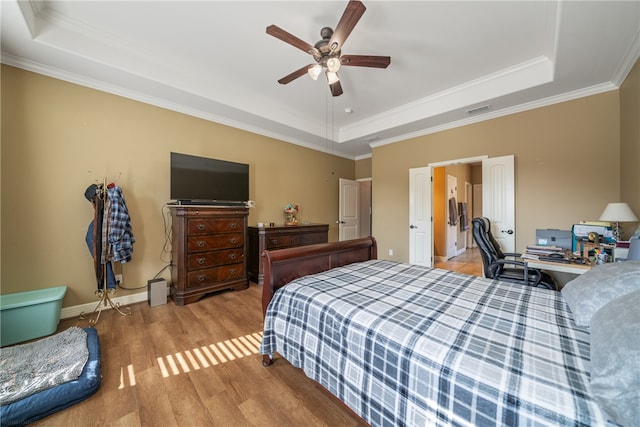 bedroom featuring light hardwood / wood-style floors, ceiling fan, a raised ceiling, and ornamental molding