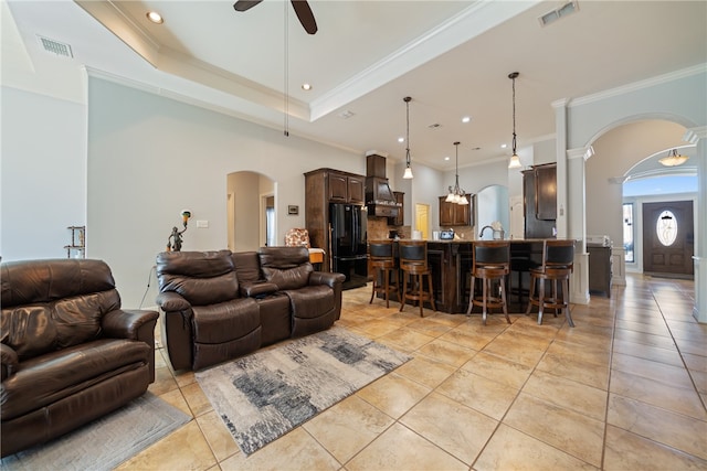 living room featuring light tile patterned flooring, ceiling fan, ornate columns, and ornamental molding