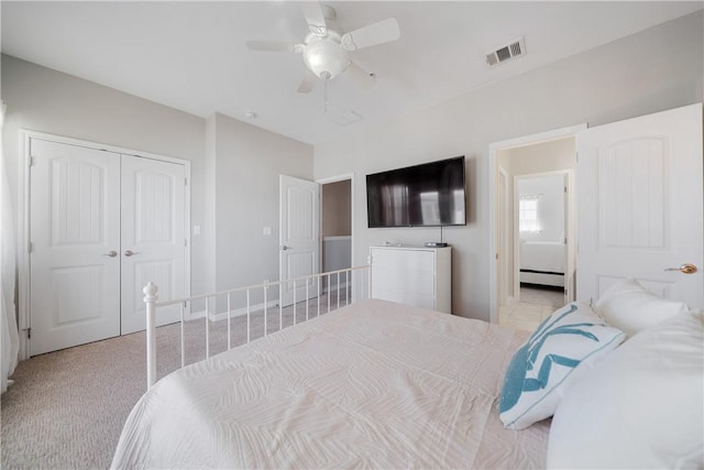 bedroom with baseboard heating, ceiling fan, a closet, and light colored carpet