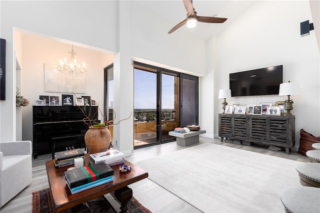 living room with wood-type flooring, ceiling fan with notable chandelier, and high vaulted ceiling