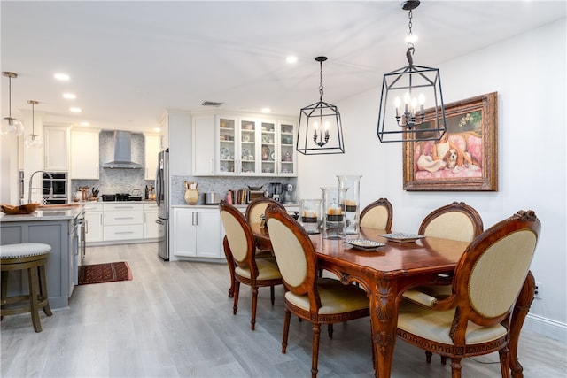 dining space featuring light hardwood / wood-style floors, sink, and an inviting chandelier