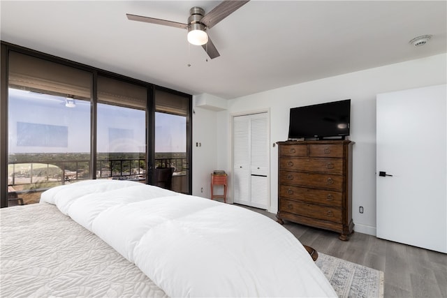 bedroom with a closet, light wood-type flooring, access to exterior, expansive windows, and ceiling fan