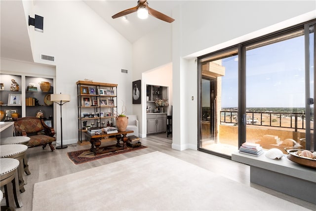 living room featuring light wood-type flooring, ceiling fan, and high vaulted ceiling