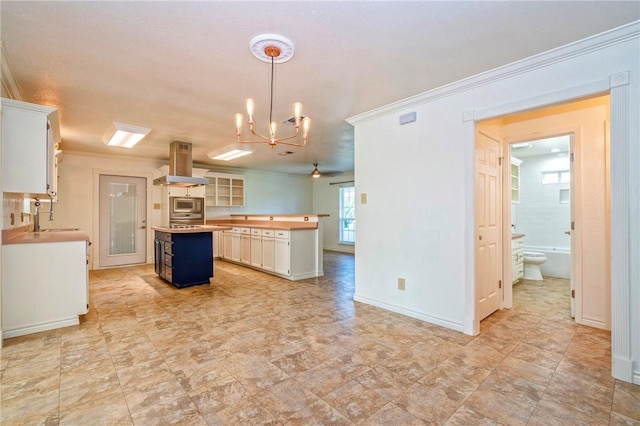 5372 County Road 73a, Robstown, TX 78380 - kitchen with exhaust hood, a chandelier, a kitchen island, stainless steel microwave, and butcher block counters