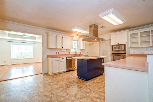 5372 County Road 73a, Robstown, TX 78380 - kitchen featuring stainless steel appliances, island range hood, white cabinetry, light countertops, and crown molding