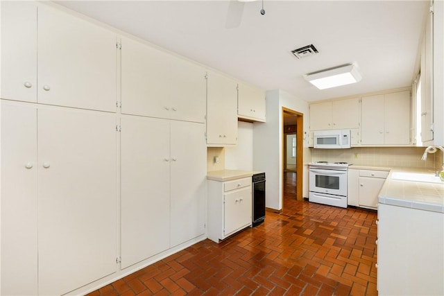 kitchen featuring sink, white appliances, white cabinets, and backsplash
