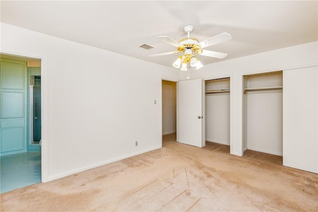 unfurnished bedroom featuring multiple closets, light colored carpet, and ceiling fan