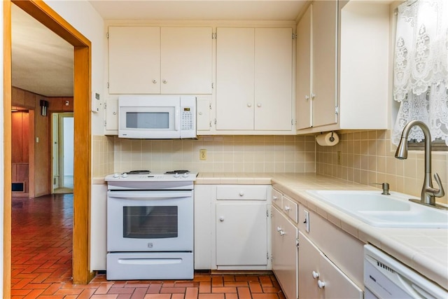 kitchen with tile countertops, sink, white cabinets, decorative backsplash, and white appliances