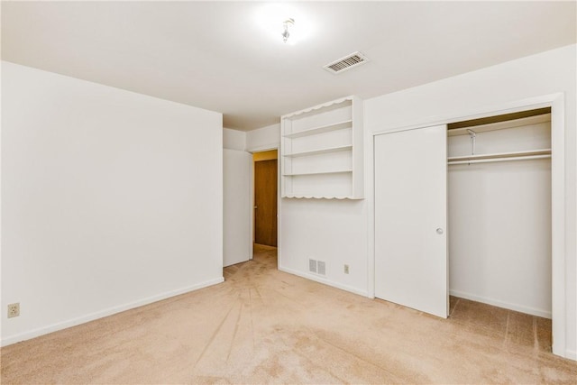 unfurnished bedroom featuring light carpet and a closet