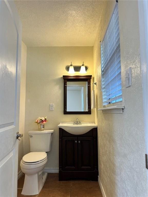 bathroom featuring vanity, tile patterned flooring, a textured ceiling, and toilet