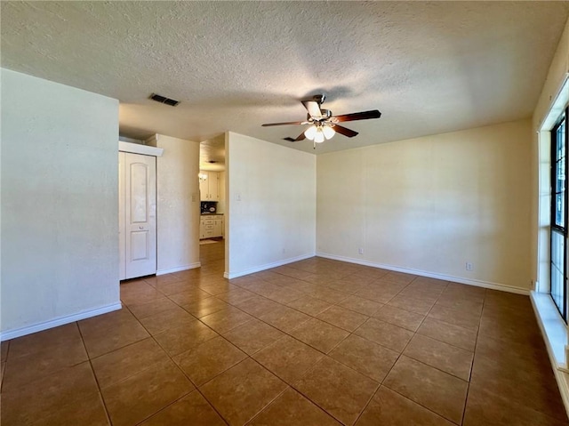 tiled empty room with a textured ceiling and ceiling fan