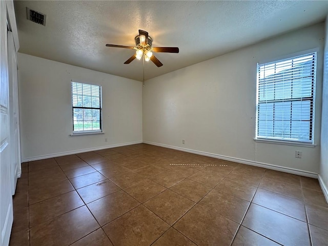 empty room with tile patterned flooring, a textured ceiling, and ceiling fan