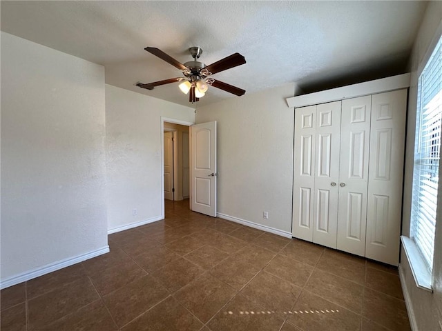 unfurnished bedroom with ceiling fan, a closet, and dark tile patterned floors