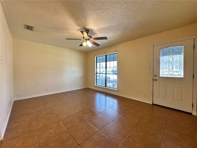 tiled entrance foyer featuring a textured ceiling and ceiling fan