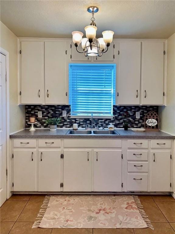 kitchen featuring sink, light tile patterned floors, white cabinets, and decorative light fixtures