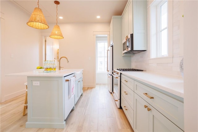 kitchen featuring decorative light fixtures, white appliances, a kitchen island with sink, decorative backsplash, and white cabinets