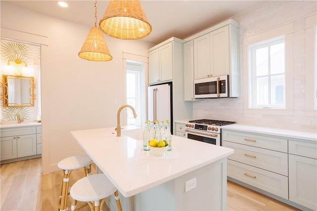 kitchen with a center island with sink, premium appliances, a kitchen breakfast bar, pendant lighting, and backsplash