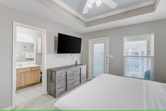 bedroom with ensuite bath, light carpet, sink, a tray ceiling, and ceiling fan