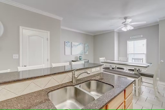 kitchen with light tile patterned flooring, ceiling fan, sink, and ornamental molding