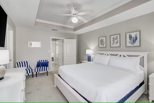 carpeted bedroom with ceiling fan and a raised ceiling