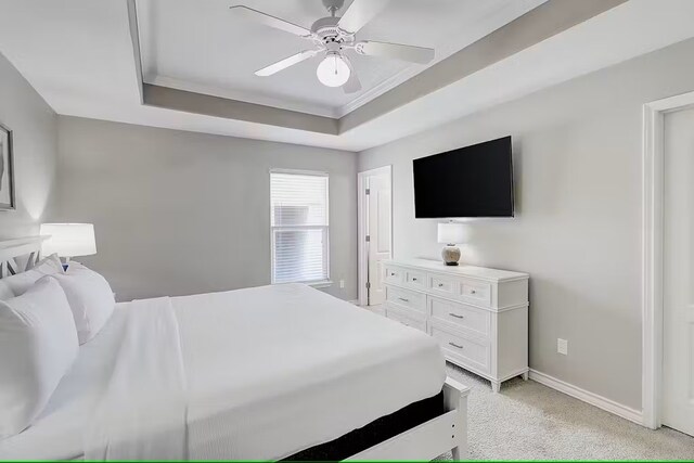 carpeted bedroom featuring ceiling fan and a raised ceiling