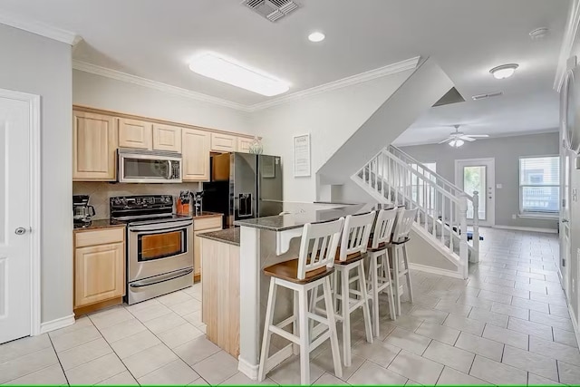 14202 Encantada Ave Unit 303, Corpus Christi, TX 78418 - kitchen featuring appliances with stainless steel finishes, light brown cabinetry, a kitchen bar, light tile patterned floors, and crown molding