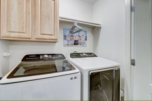 clothes washing area featuring cabinets and washer and dryer