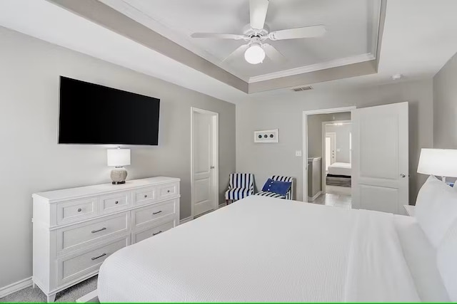 bedroom with ensuite bath, ceiling fan, and a raised ceiling