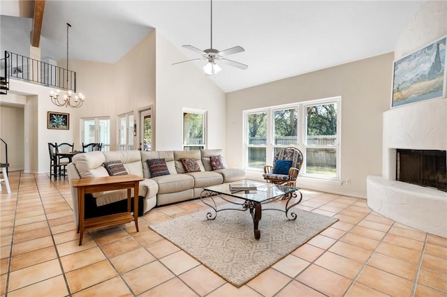 living area with light tile patterned floors, high vaulted ceiling, ceiling fan with notable chandelier, a premium fireplace, and baseboards