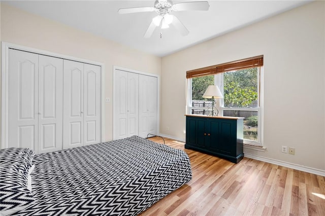 bedroom featuring multiple closets, light wood-style flooring, baseboards, and a ceiling fan