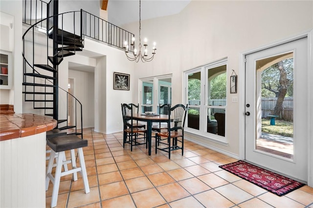 dining area with a towering ceiling, light tile patterned floors, stairs, and a notable chandelier