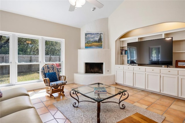 living room featuring light tile patterned floors, a fireplace, a ceiling fan, built in features, and vaulted ceiling