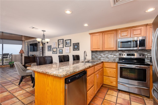 kitchen featuring a kitchen breakfast bar, appliances with stainless steel finishes, kitchen peninsula, and sink