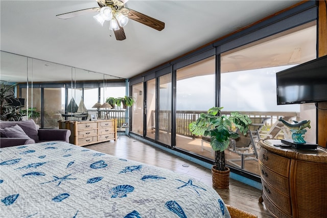 bedroom with ceiling fan, hardwood / wood-style flooring, access to exterior, and a wall of windows