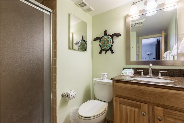 bathroom featuring toilet, vanity, and a shower with shower door