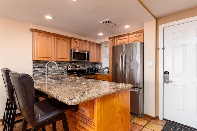 kitchen featuring tasteful backsplash, appliances with stainless steel finishes, stone countertops, sink, and kitchen peninsula