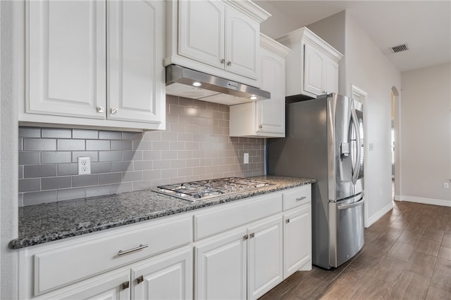 kitchen with dark stone counters, decorative backsplash, dark hardwood / wood-style flooring, white cabinetry, and stainless steel appliances