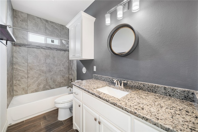 full bathroom featuring vanity, tiled shower / bath combo, and toilet