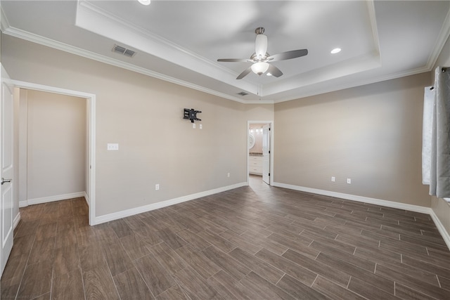 empty room with a tray ceiling, ceiling fan, dark hardwood / wood-style flooring, and ornamental molding