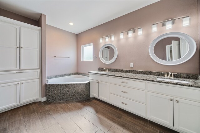 bathroom featuring hardwood / wood-style floors, vanity, and a tub to relax in