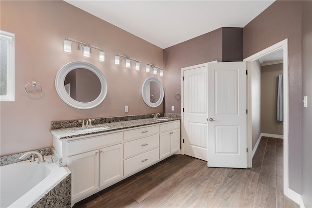 bathroom with hardwood / wood-style floors, vanity, and a relaxing tiled tub