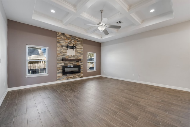 unfurnished living room featuring hardwood / wood-style flooring, a stone fireplace, and a healthy amount of sunlight